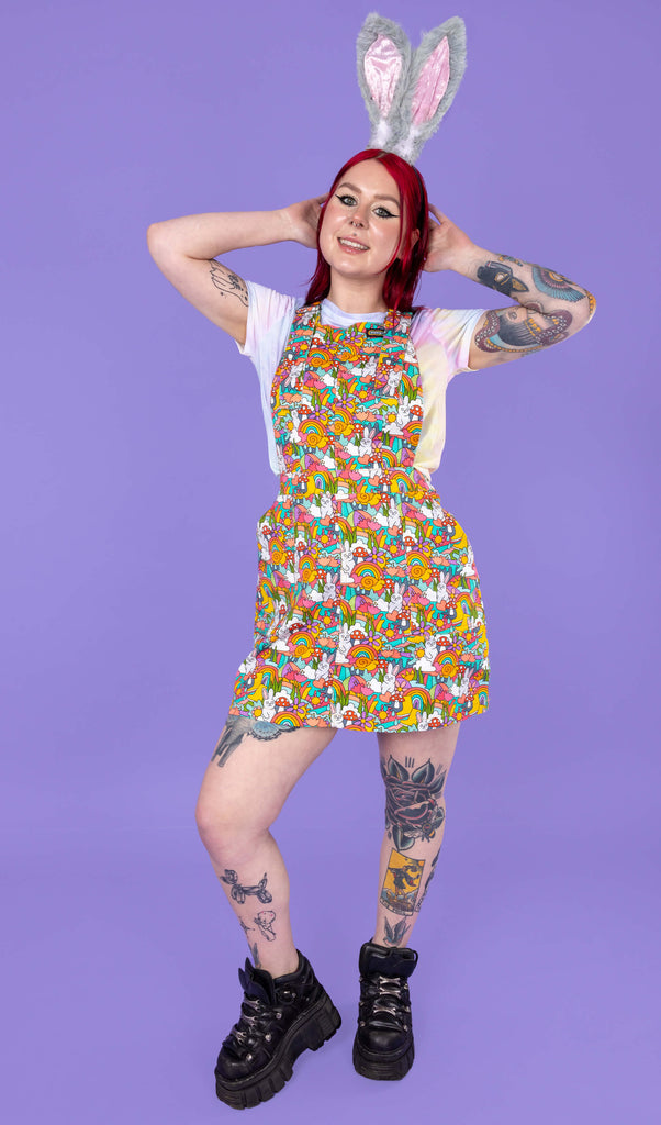 Florence a red haired tattooed femme white model wearing a Waffle Mama Design print pinafore in multi colours. Flo is wearing bunny ears.