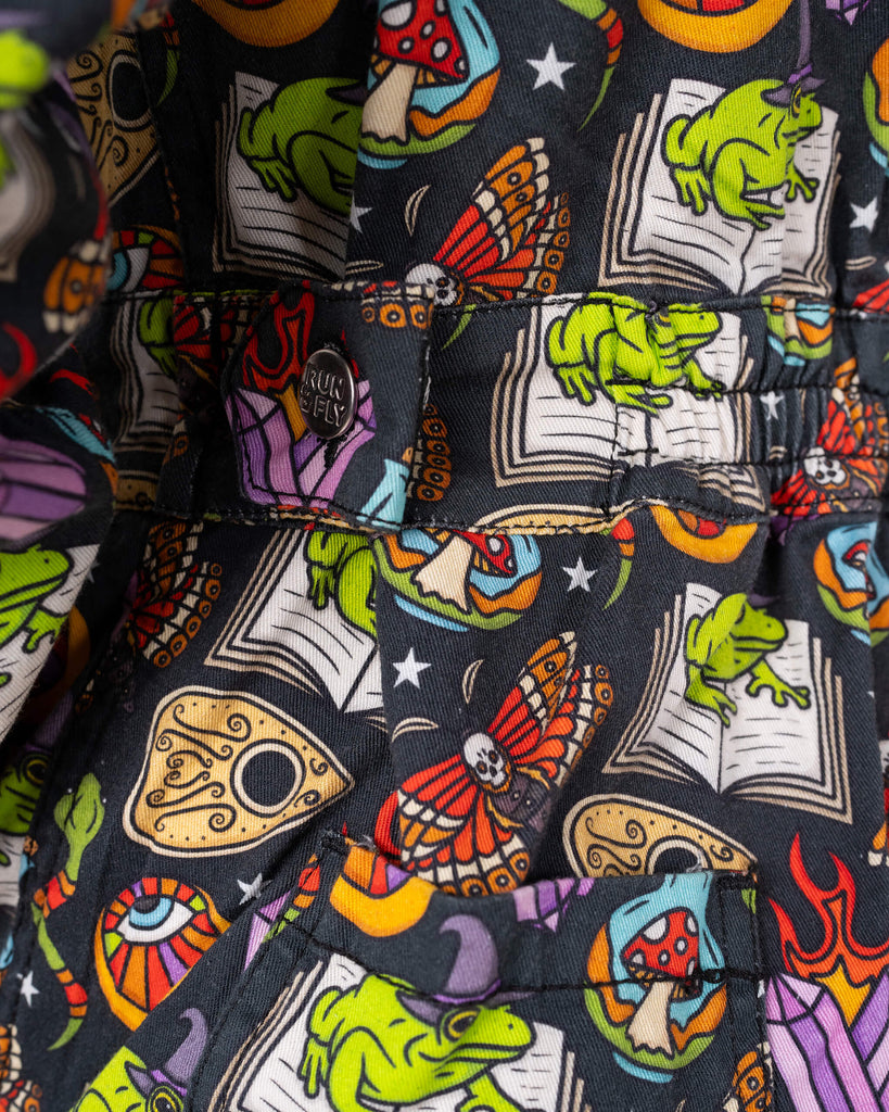 Close-up of the Run & Fly logo button detail on the Halloween: Bewitched Boiler Suit. Featuring a spooky design with frogs, skulls, and potions, this ethical slow fashion piece is perfect for quirky wardrobe additions.