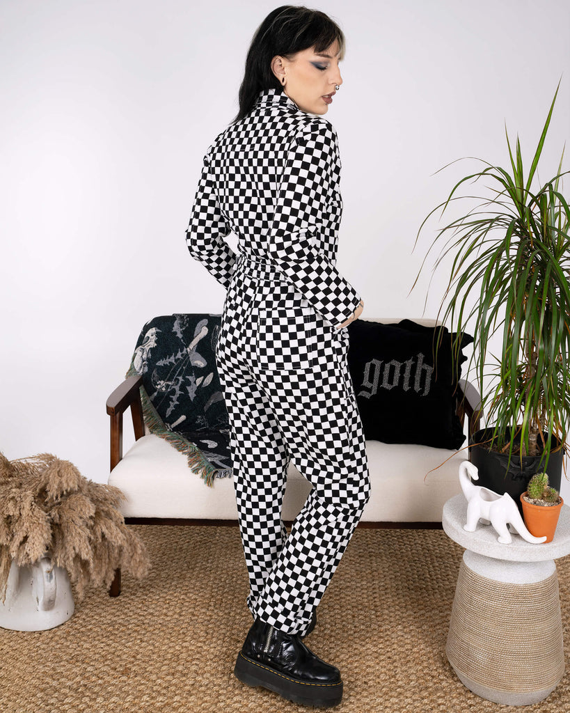 Side view of a model wearing the Black & White Checkerboard Stretch Twill Boiler Suit by Run & Fly. The bold checkerboard pattern and practical pockets make it a standout ethical fashion choice.