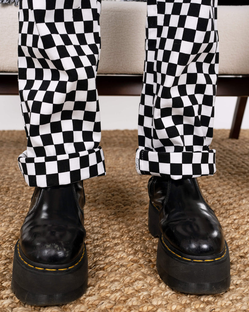 Close-up of the model’s boots paired with the Black & White Checkerboard Stretch Twill Boiler Suit by Run & Fly. Cuffed hems show the fabric’s quality, perfect for an ethical and bold everyday look.