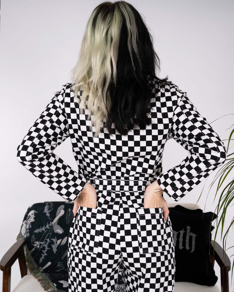 Back view of the Black & White Checkerboard Stretch Twill Boiler Suit by Run & Fly. The model poses with hands on hips, highlighting functional back pockets and an elasticated waist. A striking slow fashion piece.