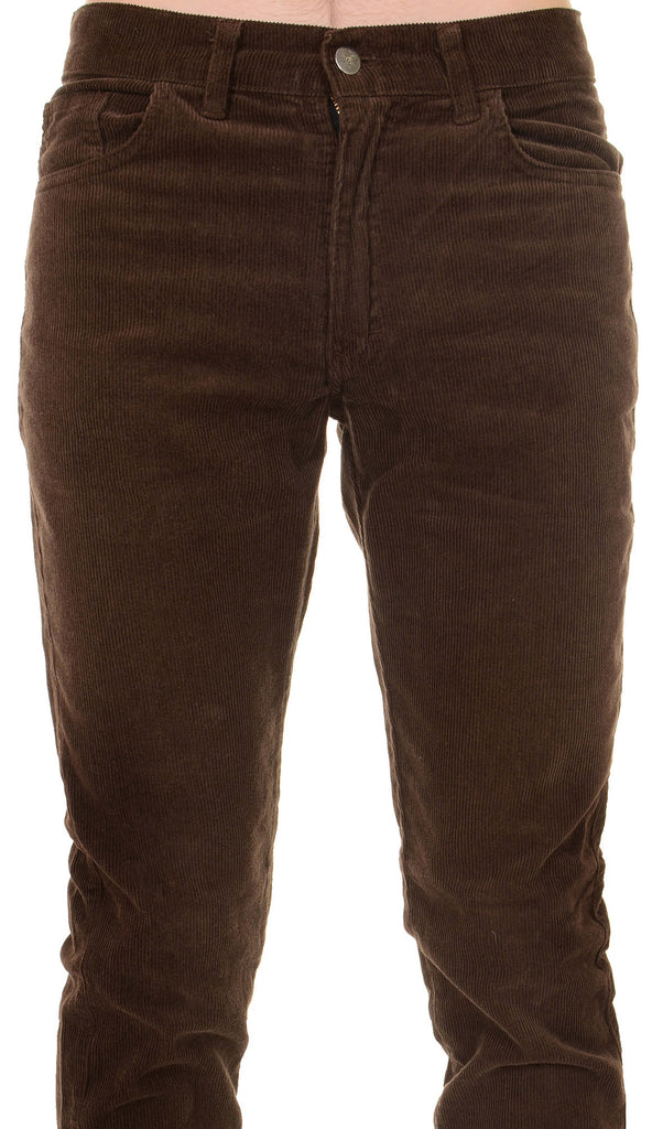 Model is stood in front of a white studio background wearing the mens 60s brown corduroy slim fit jeans with black trainers. They are facing towards the camera. Photo is cropped from the waist down.