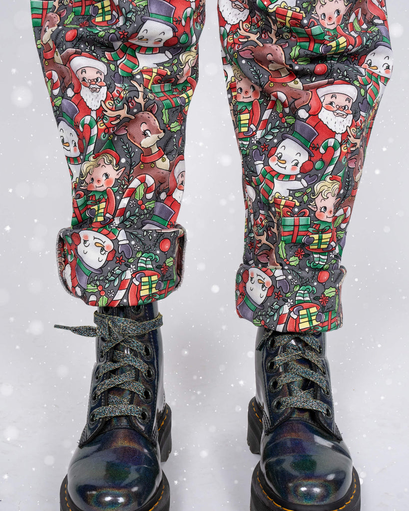 A festive focus on the rolled cuffs of Run & Fly Christmas dungarees, revealing a playful holiday print. Karina pairs the dungarees with metallic iridescent boots and glittery shoelaces for a bold, seasonal look.