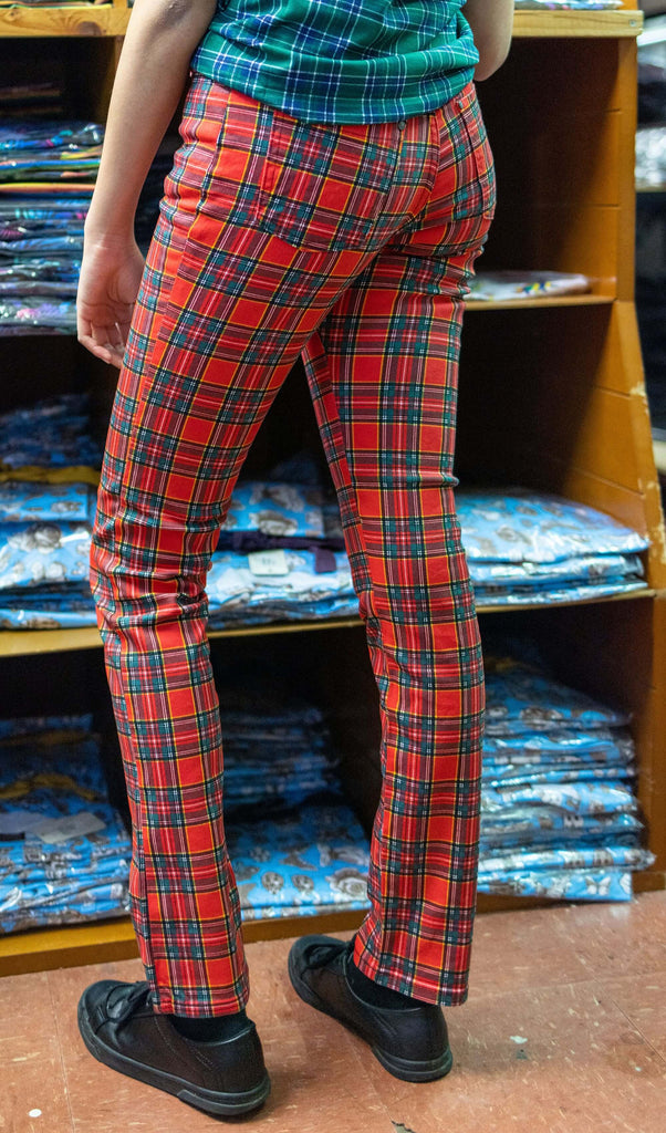 Model is stood in our warehouse wearing the mid rise red tartan stretch skinny jeans with a green tartan tshirt and black trainers. They are facing away from the camera to highlight the back details. Photo is cropped from the waist down.