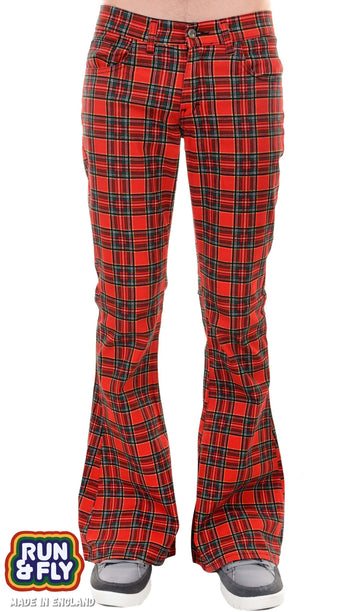 Model is stood in front of a white studio background wearing the red tartan plaid bell bottom flares with grey trainers. They are facing forward and photo is cropped from the waist down.