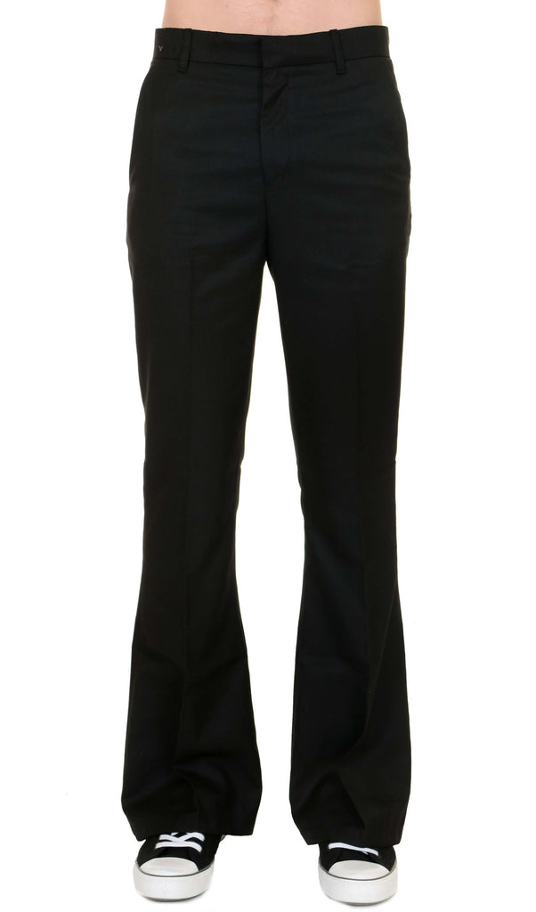 Model is stood in front of a white studio background wearing the Presley black bell bottom trouser slacks with black trainers. They are facing forward and photo is cropped from the waist down.