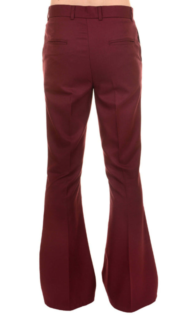 Model is stood in front of a white studio background wearing the Presley burgundy bell bottom trouser slacks with black trainers. They are facing away from the camera and photo is cropped from the waist down.