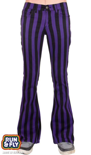Model is stood in front of a white studio background wearing the purple and black striped bell bottom stretch super flares with grey trainers. They are facing forward and photo is cropped from the waist down.