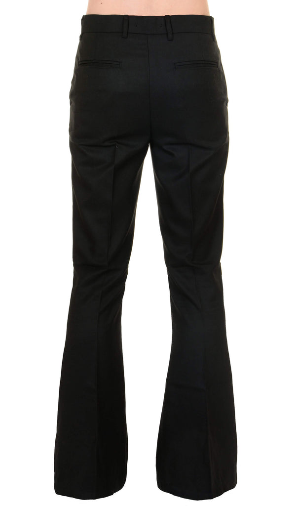 Model is stood in front of a white studio background wearing the Presley black bell bottom trouser slacks with black trainers. They are facing away from the camera and photo is cropped from the waist down.