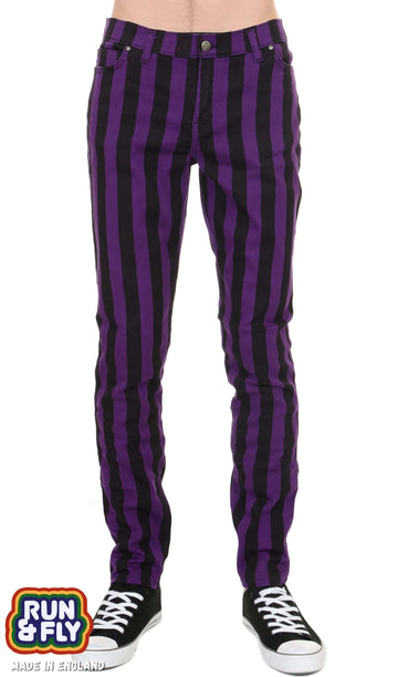 Model is facing the camera wearing purple and black vertically striped skinny jeans with black converse trainers. Photo is cropped from the waist down.