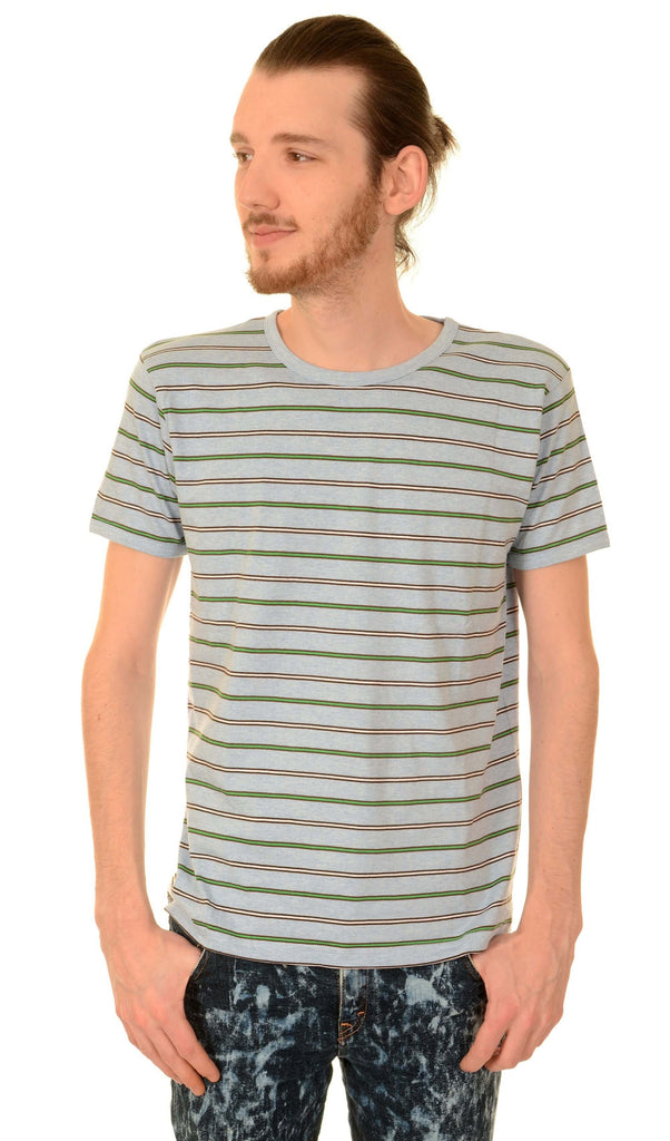 Model in front of a white background, wearing the retro sky marl pin striped tee. He is facing the camera with his hands in his pockets looking off to one side.