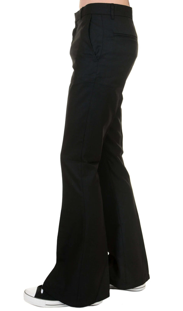 Model is stood in front of a white studio background wearing the Presley black bell bottom trouser slacks with black trainers. They are facing to the left with one leg forward to highlight the flared bottoms. Photo is cropped from the waist down.