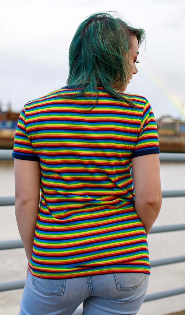 Kat, facing away from the camera, with bright green hair and matching eyebrows wearing the Retro Rainbow Brights Repeat Striped T Shirt and light blue jeans