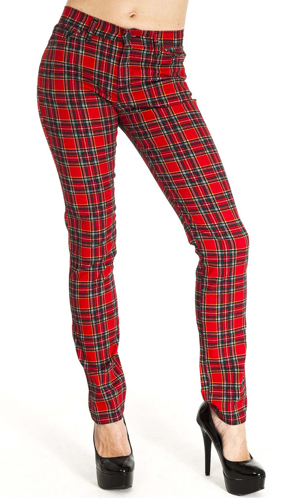 Model is stood in front of a white studio background wearing the mid rise red tartan stretch skinny jeans with black heels. They are facing the camera with one leg out to the side. Photo is cropped from the waist down.