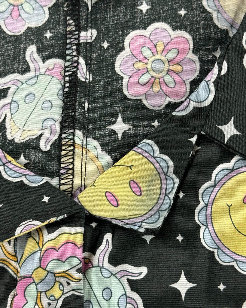 Detail shot of a Bee Happy Stretch Jumpsuit top collar from Run & Fly, a small ethical slow fashion brand. A yellow sun print appears faded and discoloured, showing a noticeable greyish patch on the collar corner.
