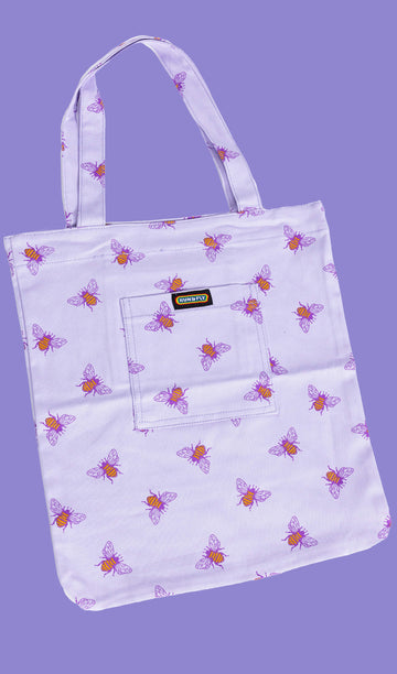 flat lay of a lilac tote bag with an all over print of yellow bumble bees with purple wings on a purple backdrop. There is a front pocket on the tote bag with Run&Fly logo on the front.