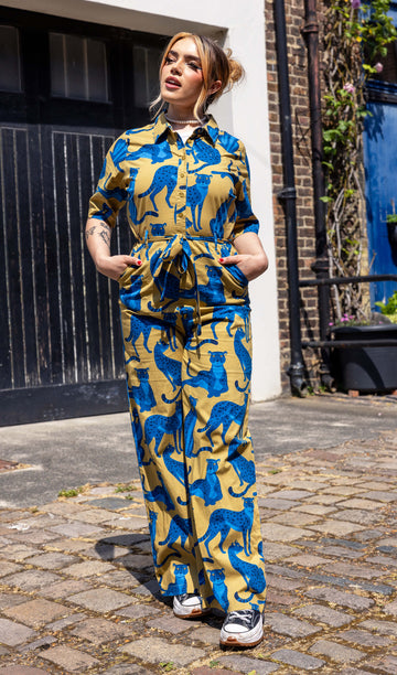 Melia is a smiley blonde model wearing a yellow jumpsuit with blue panthers on and is stood in a mews in Hove shot by Amy Davies Photography
