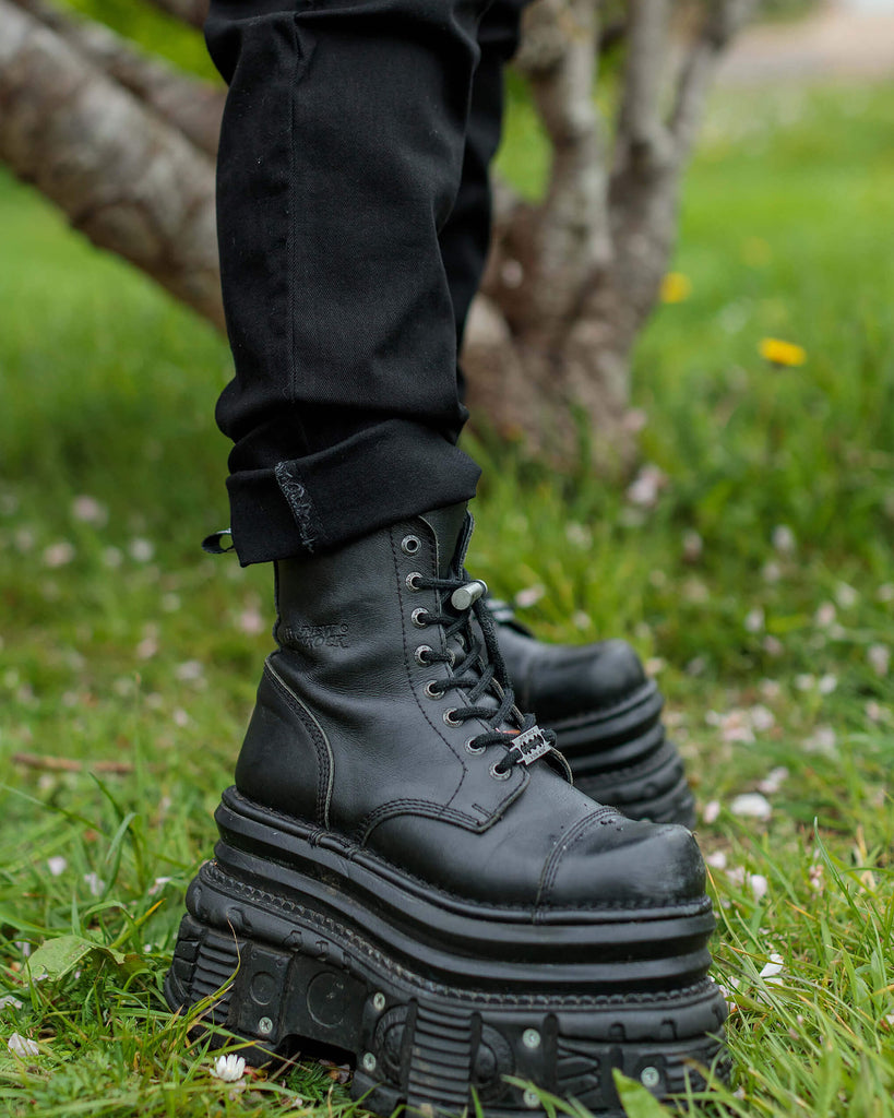 Close up of Florence's legs, wearing the Black Stretch Denim Dungarees, slightly rolled at the ankle, to show off black platform boots.