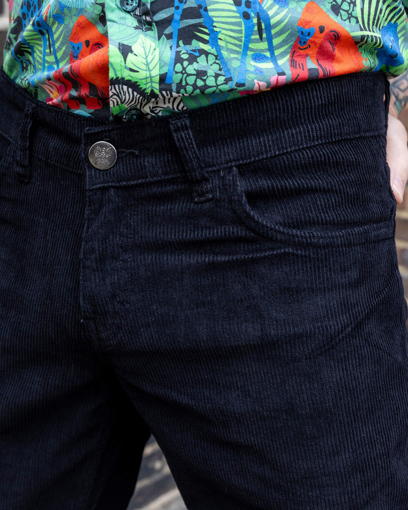 close up of Jim is standing in a mews in Hove he is a tattooed grey haired man he is wearing a jungle print shirt and black flares by Run & Fly