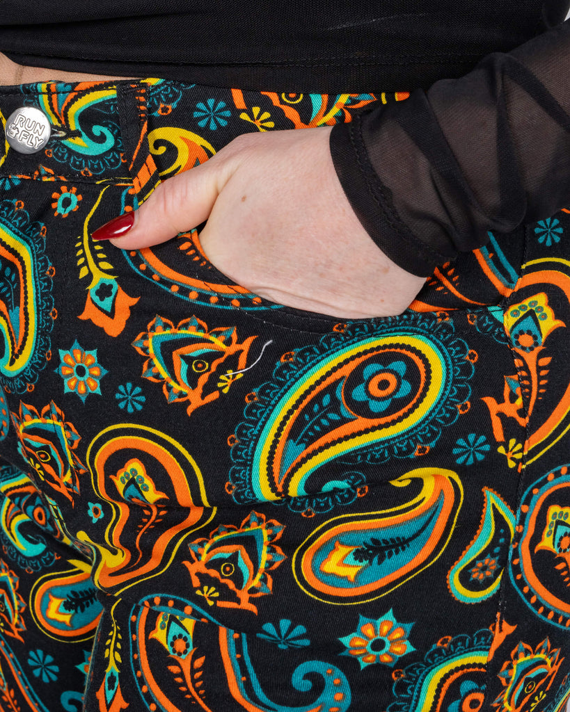A detailed shot of the front pocket of the black paisley flares by Run & Fly. The retro-inspired print blends bold orange, turquoise, and yellow tones, perfectly reflecting the brand's ethical slow fashion ethos.