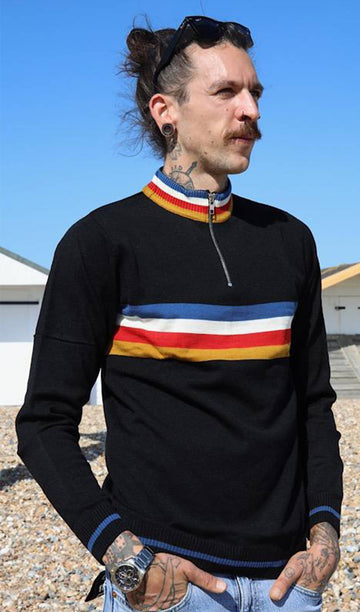 Tattooed model is standing in front of a bright blue sky with sunglasses on his head and wearing the Black Lightning Rainbow Cropped Jumper