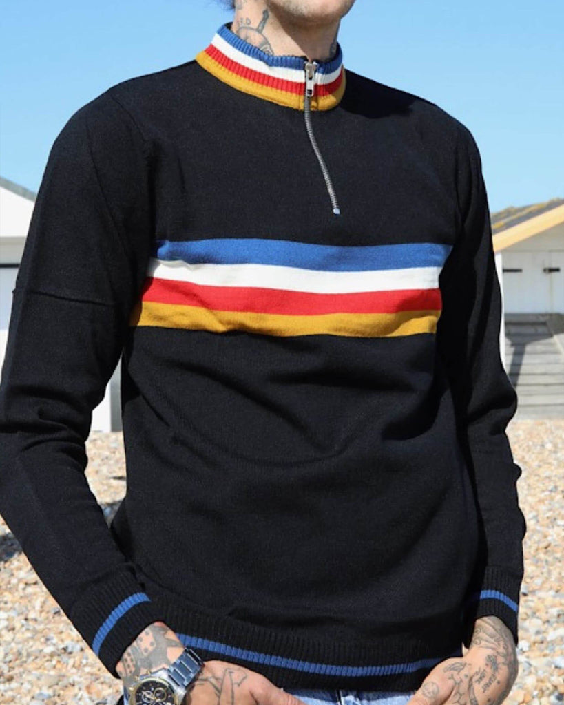 Tattooed model is standing in front of a bright blue sky with sunglasses on and wearing the Black Lightning Rainbow Cropped Jumper
