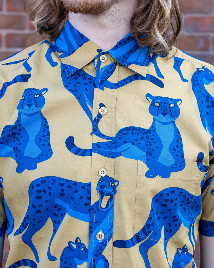 Jack is stood in front of a brick wall wearing the blue leopard short sleeve shirt. Photo is close cropped in on the collar and button detailing from chin to waist.