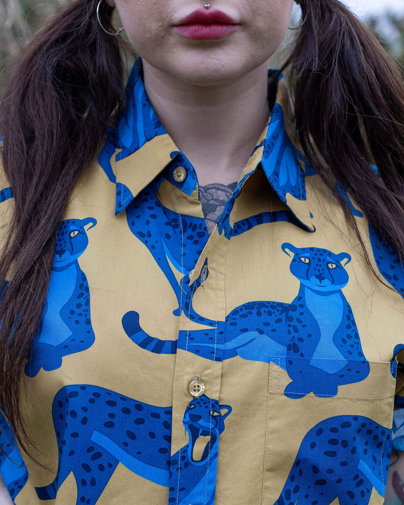 Florence is stood in a garden wearing the blue leopard short sleeve shirt. Photo is close cropped in on the collar and button detailing from chin to waist.