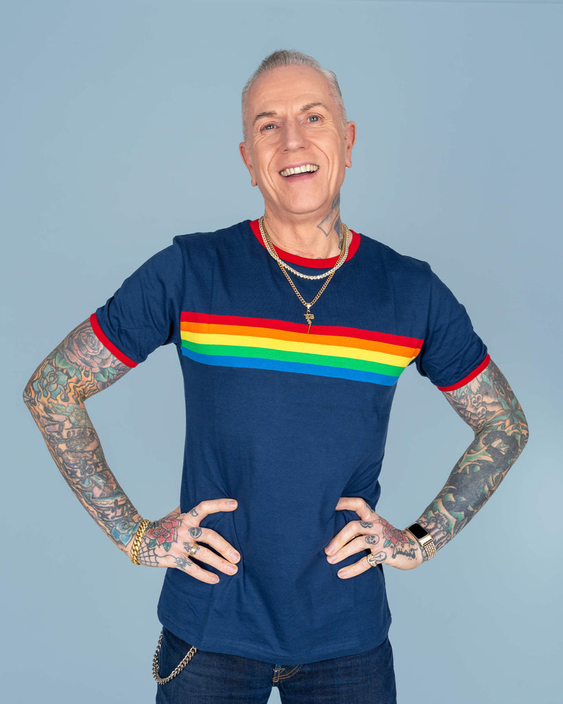 James strikes a playful pose in the navy rainbow t-shirt, showing off the vivid rainbow stripe and red accents. The tattoos and accessories bring personality to the outfit, while the shirt’s classic fit is perfect for any casual wardrobe.