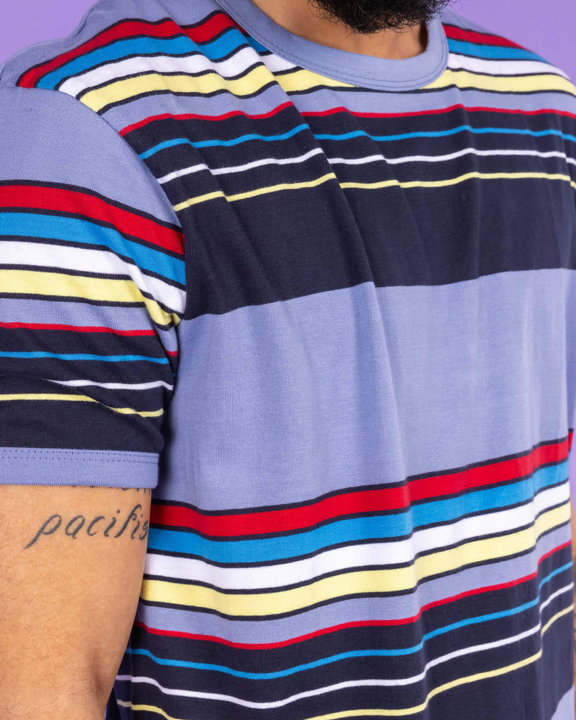 Close up of Richard wearing the Vintage Blue Stripe Tee. The blue t shirt has horizontal lines in red, blue, white, yellow and navy.