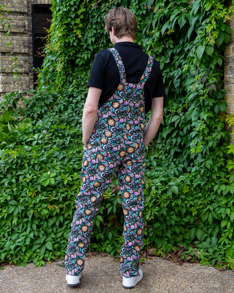 Jack Roper stands with his back to the camera, modelling Run & Fly’s “Boho Summer” dungarees. The lively, colourful print pops against the green backdrop, emphasising the brand’s commitment to bold, ethical, and slow fashion.