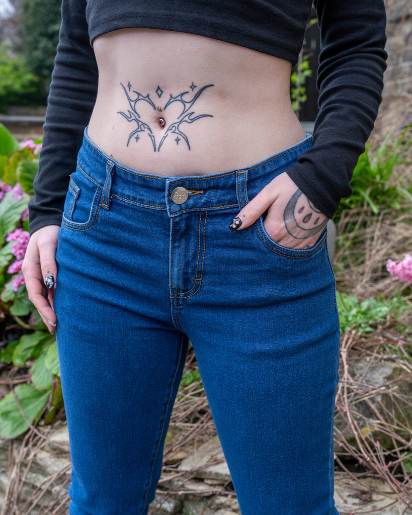 Front close-up of stonewash denim bootcut jeans with visible waistband, button, and pocket details.