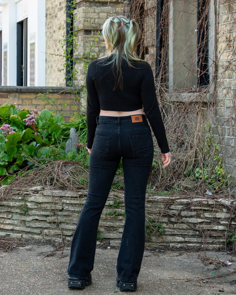 Back view of a person wearing Run & Fly Black Stretch Denim Slim Bootcut Jeans, paired with a long sleeve black crop top. The jeans have a flattering slim fit with a subtle bootcut flare. Ethically made, UK slow fashion.