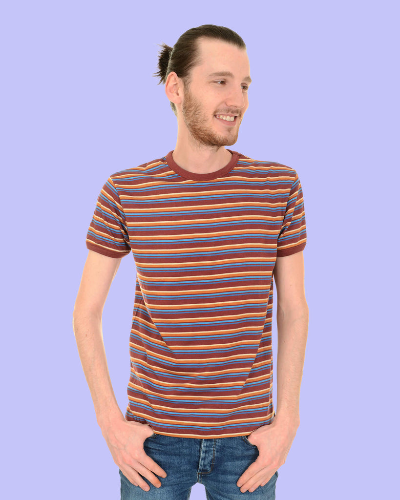 Model is standing in front of a white background with hands on hips, wearing the Burgundy Stripe Retro T Shirt with blue jeans