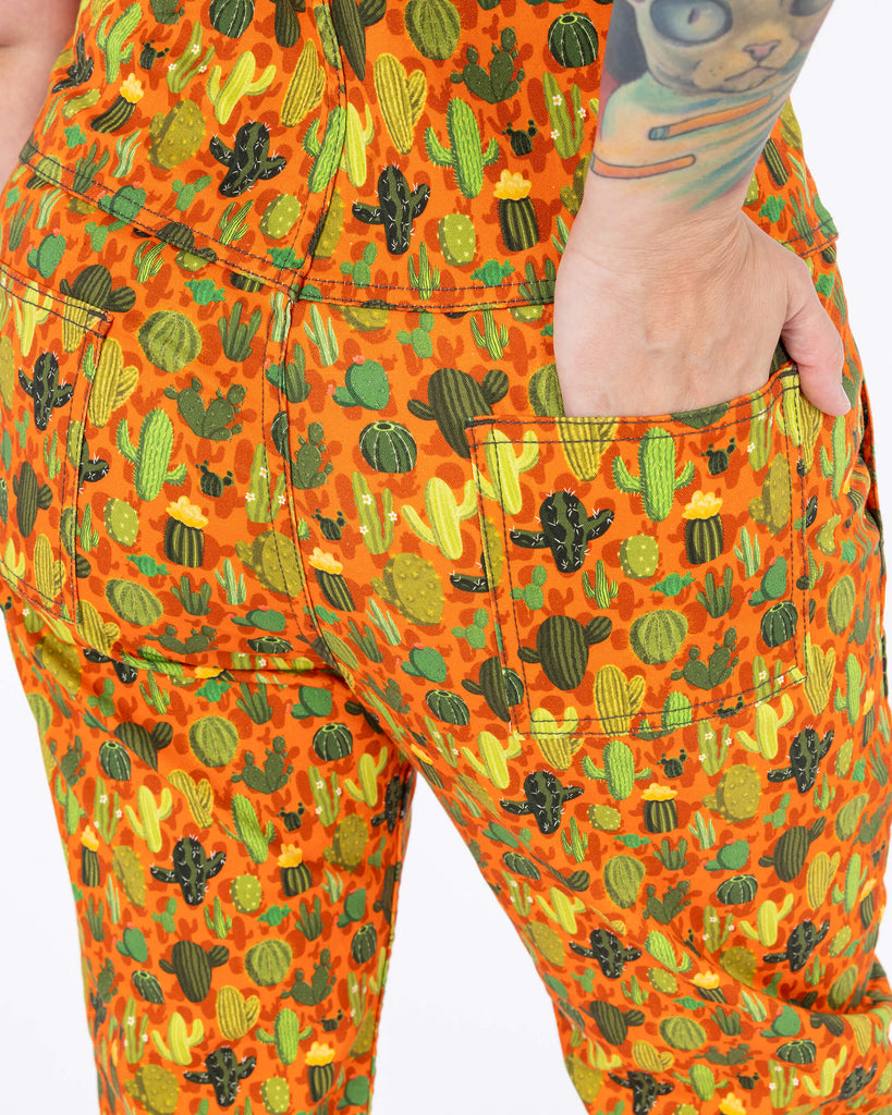 close up of Cactus Stretch Twill Dungarees. Close up shows the upturned legs of the dungarees with white trainers underneath. The photo is taken in front of a white backdrop in a studio in Hove.