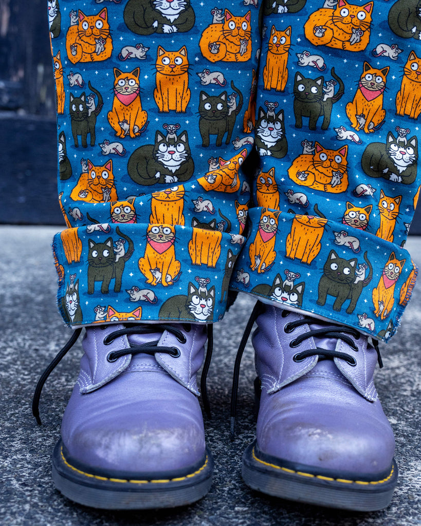 Detail shot of the “Cat and Mouse” print on the Run & Fly dungarees. The bright blue fabric is decorated with illustrations of playful cats and mischievous mice, perfect for animal lovers.