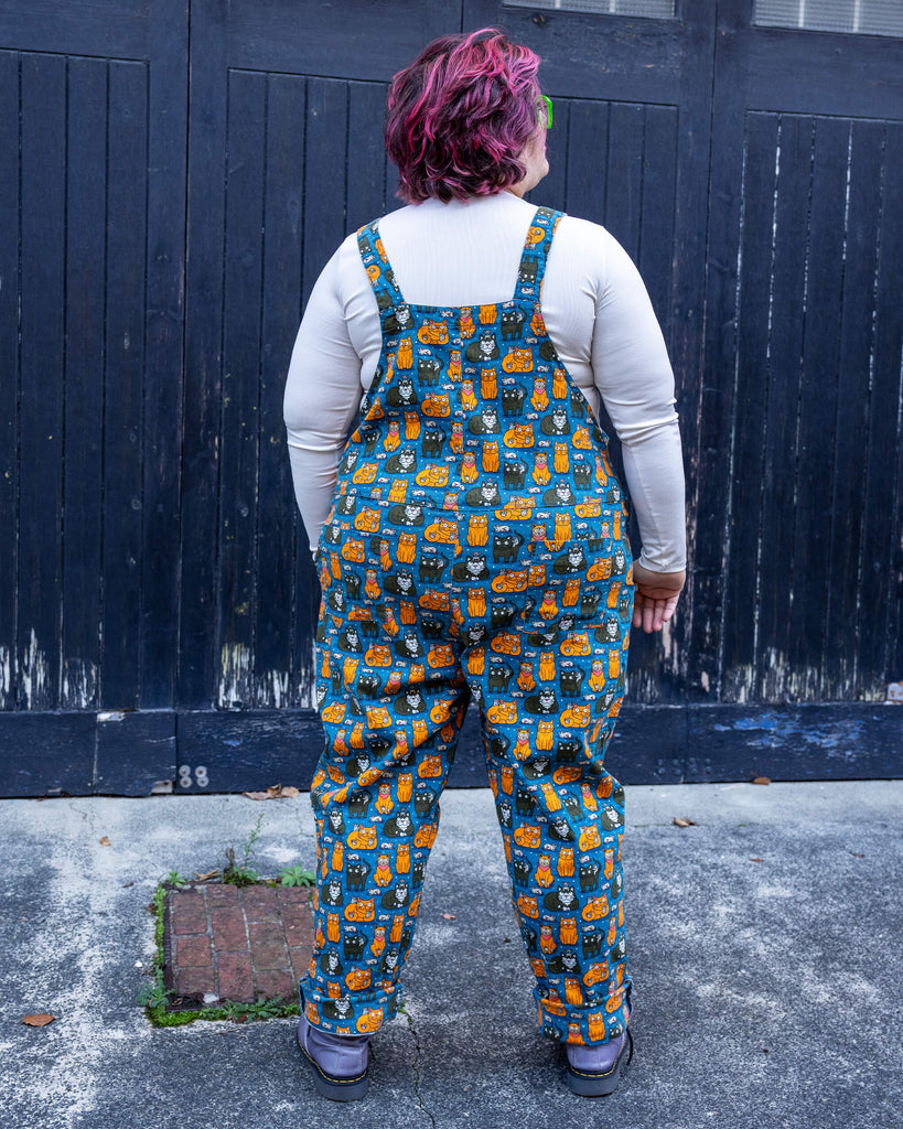 Back view of Jackie in the “Cat and Mouse” dungarees by Run & Fly. The seamless continuation of the whimsical print showcases its vibrant and fun design.