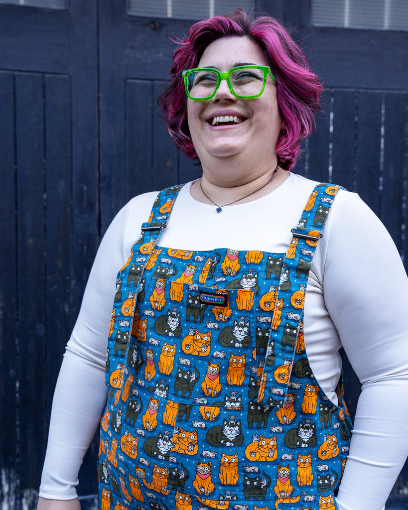 Close-up of Jackie in the “Cat and Mouse” dungarees. The bold print, with cats in various poses and tiny mice, creates a whimsical and cheerful look.