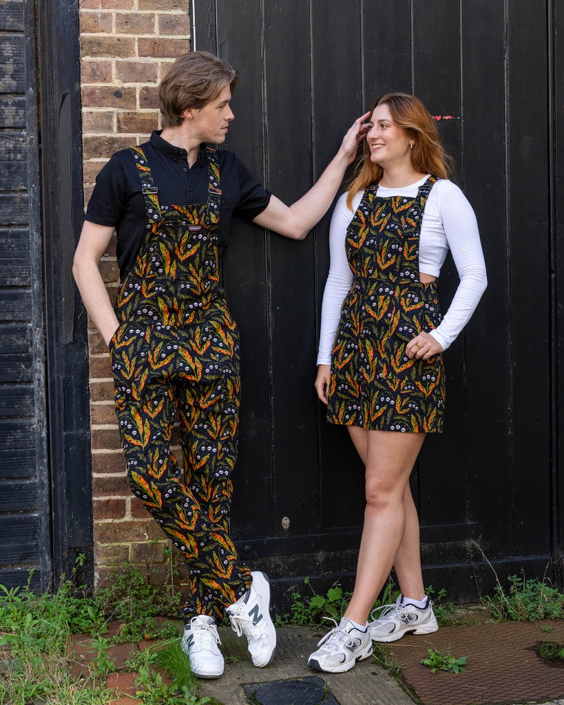 Two models wearing matching Run & Fly poison-print outfits. The small British brand offers ethical, slow fashion with quirky designs, including a poison pinafore dress and dungarees featuring a bold skull and leaf pattern. Ideal for those who love to coordinate their style with sustainable, alternative fashion.
