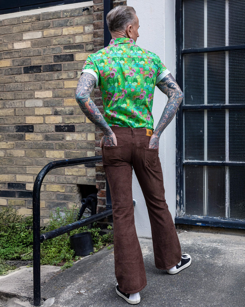 Back photo of James a tattooed white male with silver hair in his 50's is posing wearing a frog print shirt and brown corduroy flares stood in a mews in Hove UK