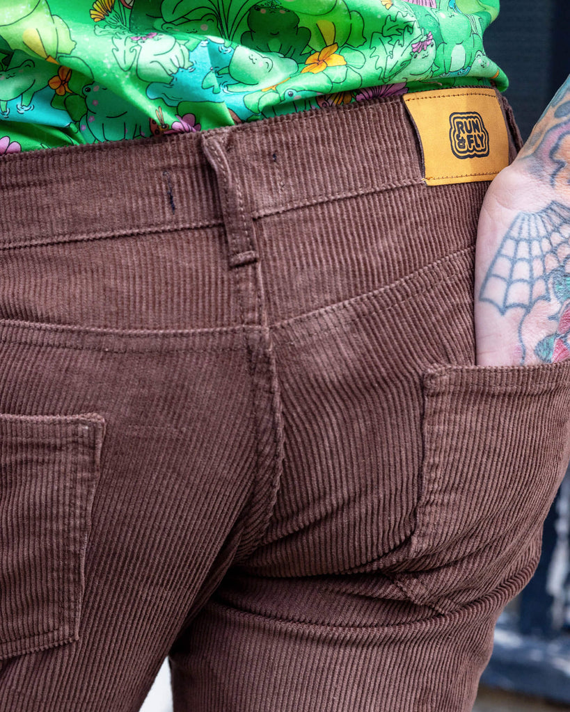 Close up of the back pocket worn by James a tattooed white male with silver hair in his 50's is posing wearing a frog print shirt and brown corduroy flares stood in a mews in Hove UK.
