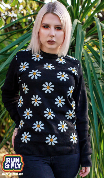 Florence is wearing the Daisy Chain Black Jumper and has a blonde sharp bob and orange eye makeup.