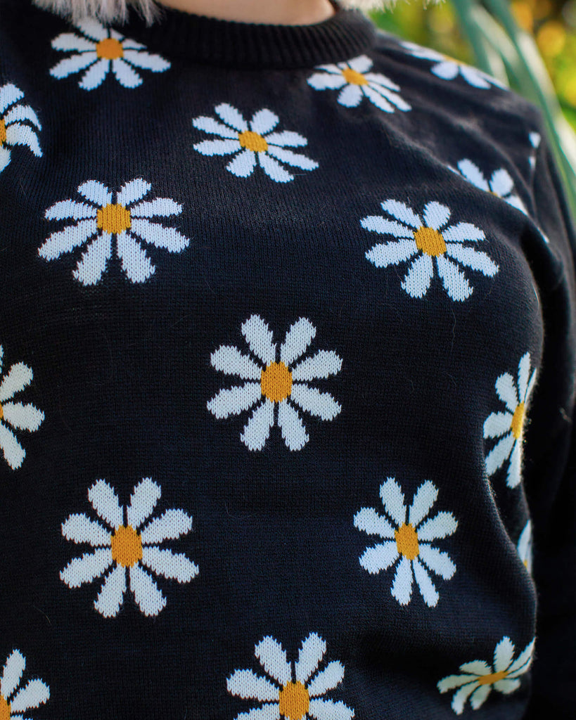 Close up of the Daisy Chain Black Jumper on Florence. The black jumper has plain black arms and back with repeating white daisies across the front body.