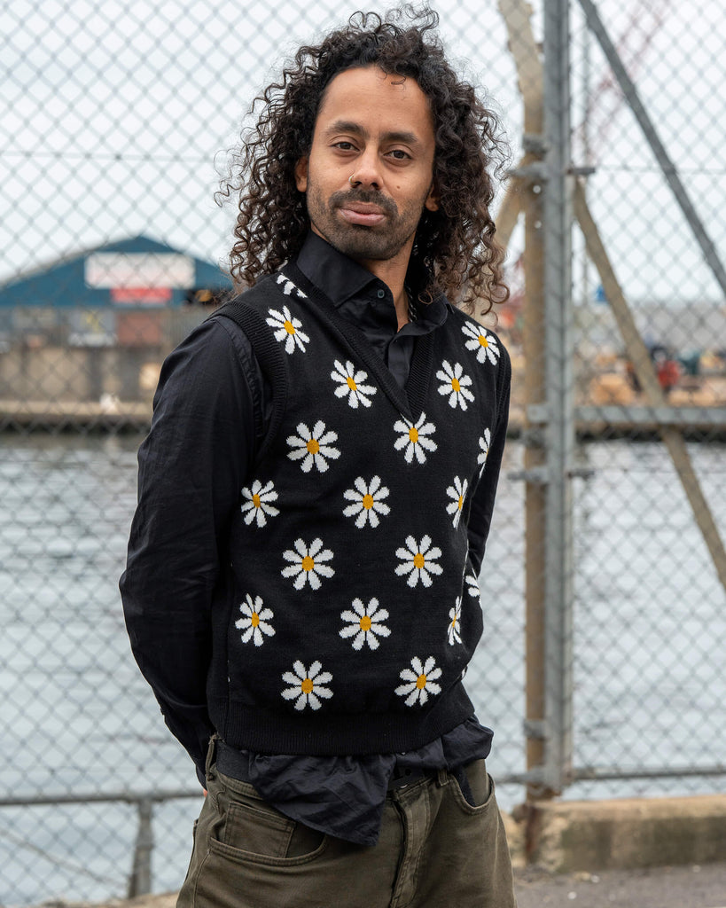 Front view of the unisex Run & Fly Black Daisy Tank Vest made in England, showing cheerful white daisy flowers with yellow centres on a black knit.
