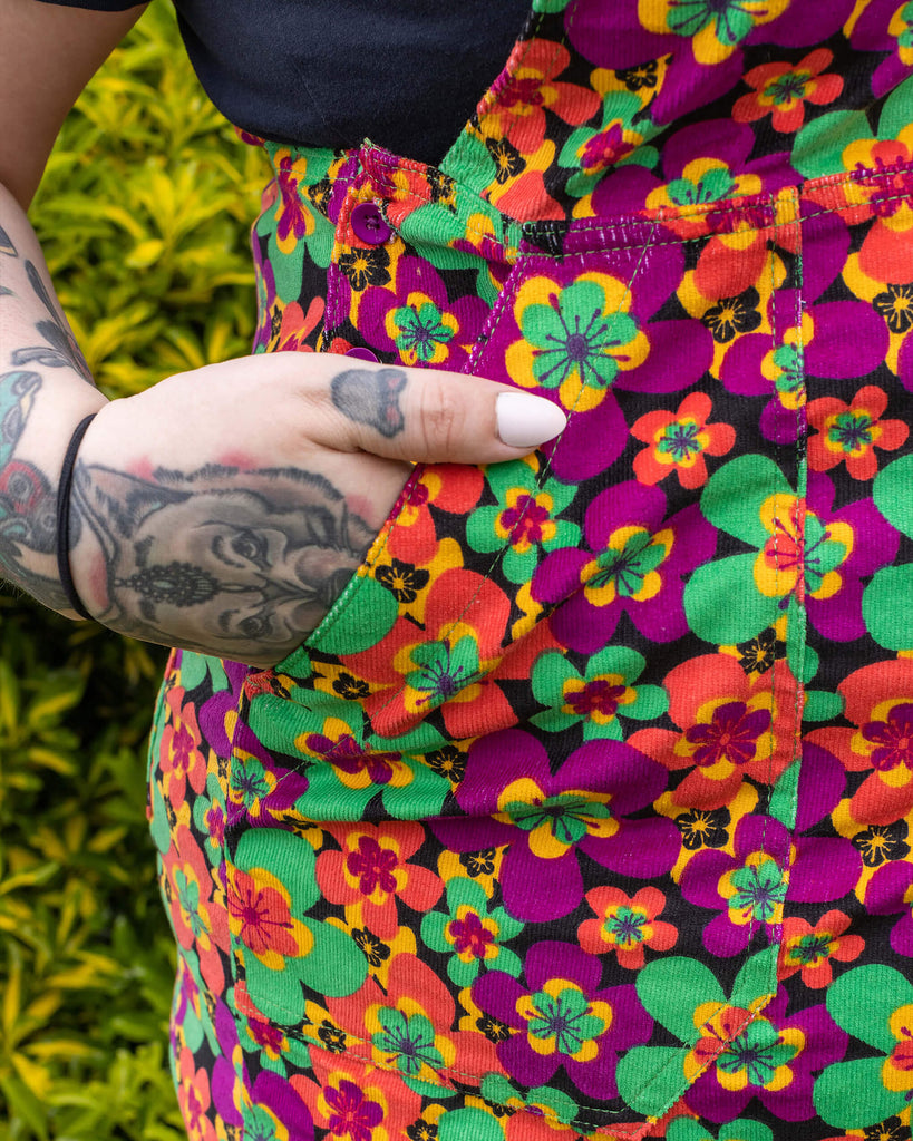 Close up of the pinafore side pocket on the 70s dark floral print stretch corduroy long pinafore dress.