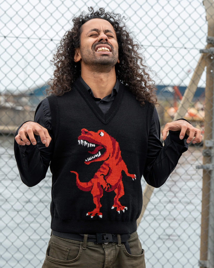Model Rich wears the Run & Fly Red Dino Tank Vest featuring a red T-Rex design on black knit. Posing playfully with a dinosaur stance.
