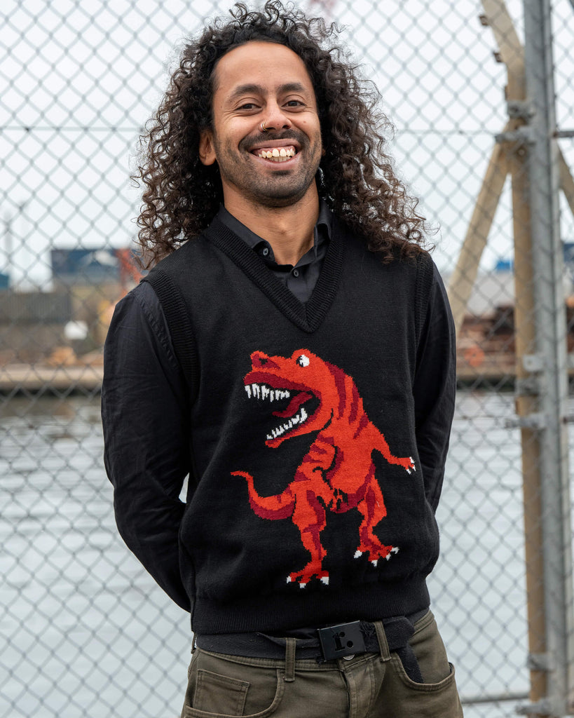 Model Rich smiles wearing the Run & Fly Red Dino Tank Vest. The design features a bold red T-Rex on a black knit for a fun retro style.