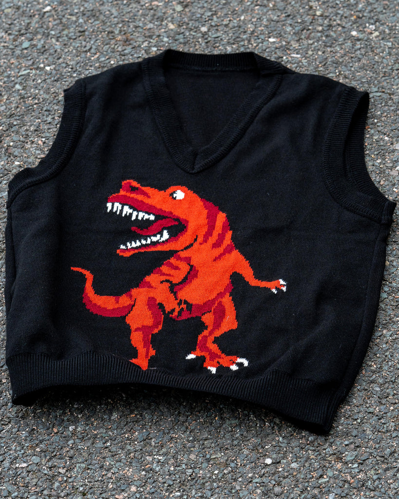 Flat lay of the Run & Fly Red Dino Tank Vest showing the red T-Rex knit on black fabric. Made in England from soft acrylic.