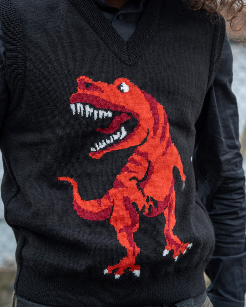 Close-up of the Run & Fly Red Dino Tank Vest showing the detailed red T-Rex knit pattern on black. Unisex and designed for layering.