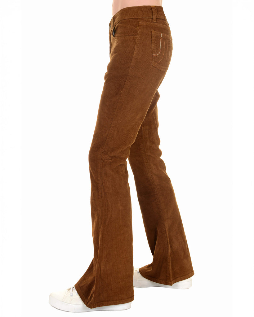 A side profile of the Tobacco Corduroy Bell Bottom Super Flare Trousers from Run & Fly. These mid-waisted trousers feature a vintage-inspired design, with a snug fit through the hips and thighs, flaring dramatically from the knee down. Made from soft, ethically sourced corduroy in a rich tobacco colour, paired with casual white trainers.